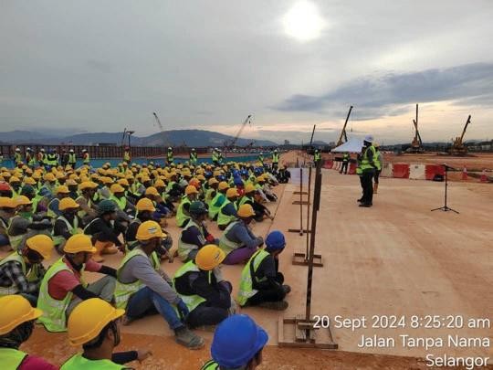 Large group of workers seated for an on-site safety briefing