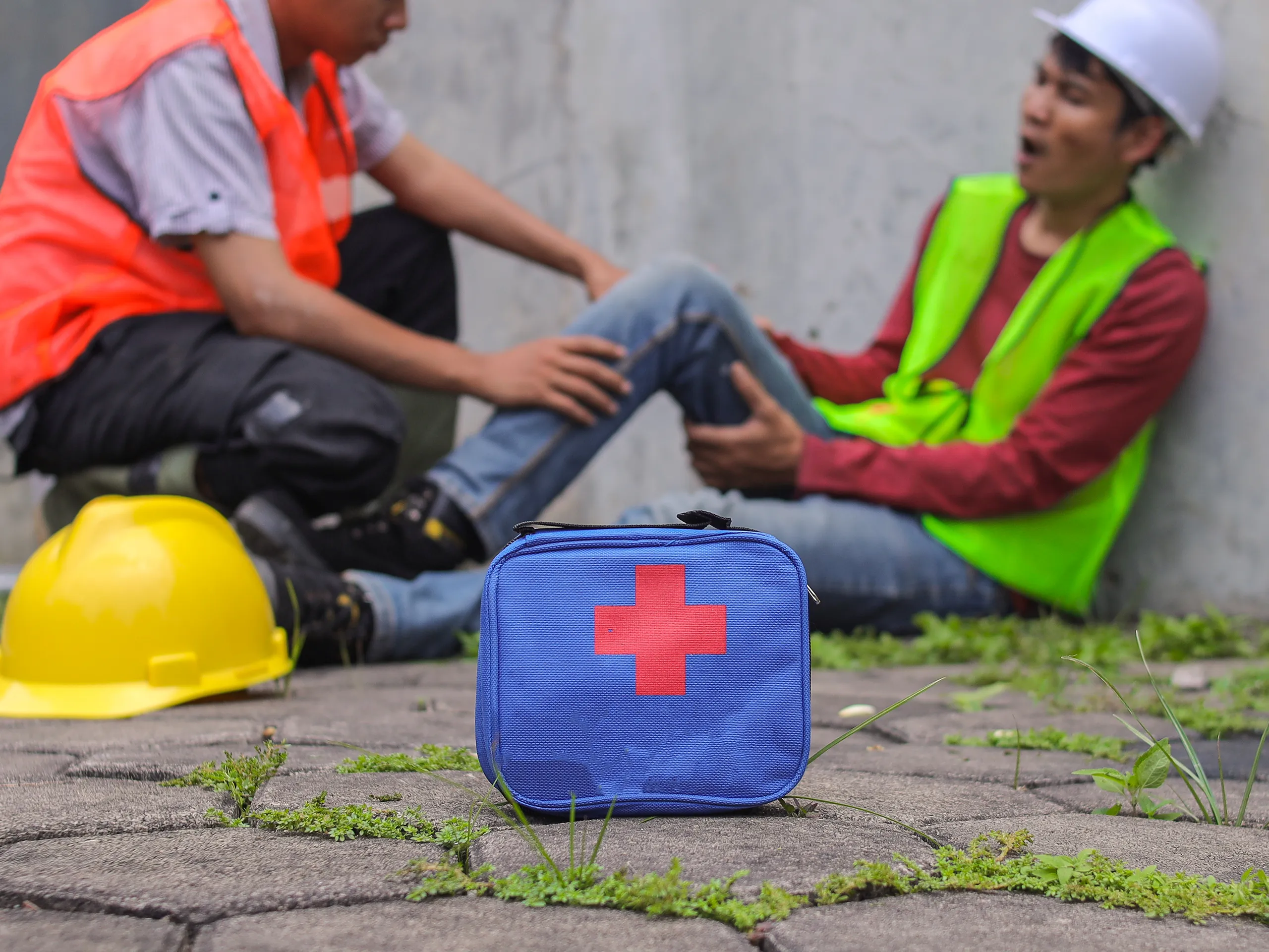 First aid kit at a worksite with a colleague attending to an injured worker
